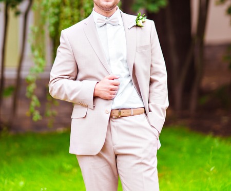 A groom putting on cuff-links as he gets dressed in formal wear .Groom's suitの写真素材