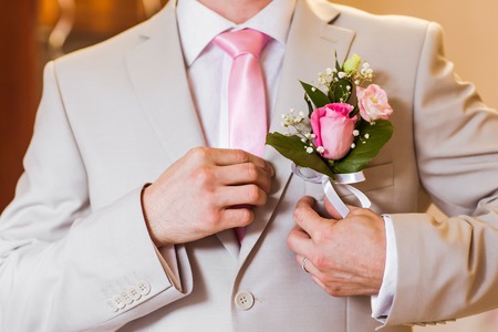 A groom putting on cuff-links as he gets dressed in formal wear .Groom's suitの写真素材