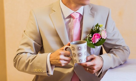 A groom putting on cuff-links as he gets dressed in formal wear .Groom's suitの写真素材