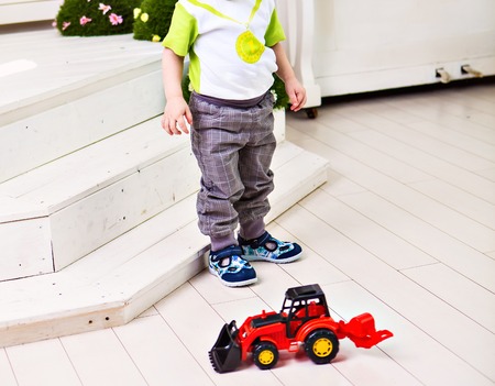 little boy plays with red toy car