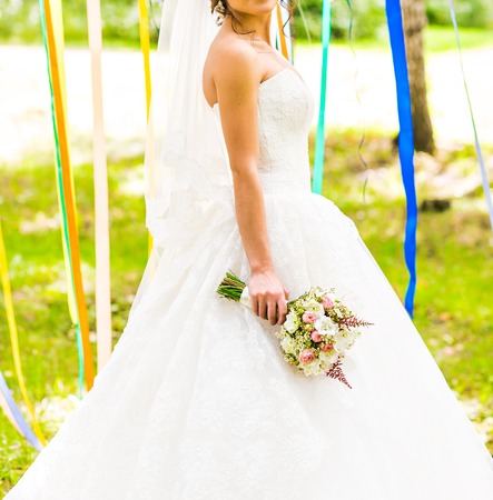 Beautiful bride outdoors in a forest with bridal bouquetの写真素材
