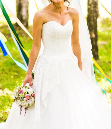 Beautiful bride outdoors in a forest with bridal bouquetの写真素材