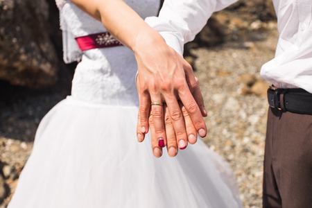 Holding Hands with wedding rings on the background of seaの写真素材