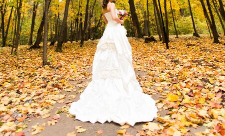 happy bride on autumn forest with bouquetの写真素材