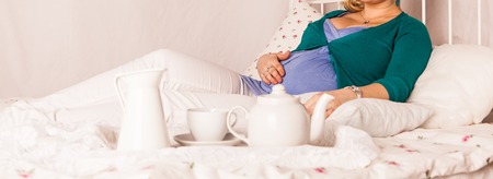 Pregnant woman relaxing at home on the bedの写真素材