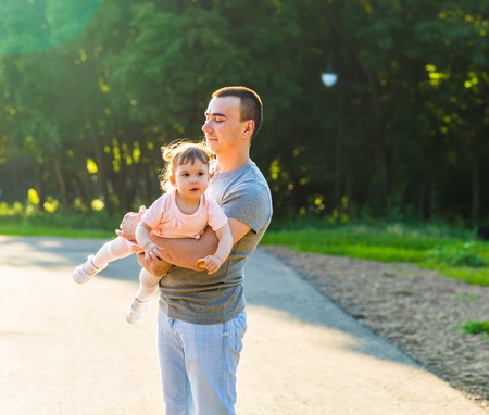 Little baby girl in a summer park with her fatherの写真素材