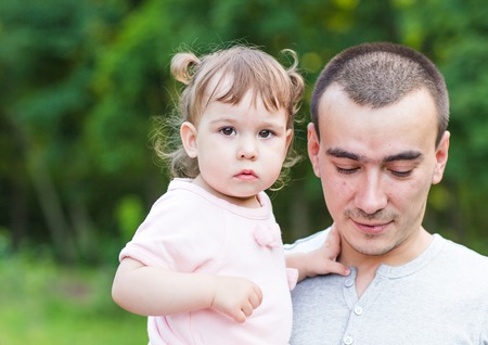 Little baby girl in a summer park with her fatherの写真素材