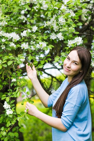 Portrait of spring brunette girl standing outdoor in blooming trees. Beautiful romantic woman in...