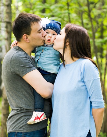 Happy young family spending time together in green nature.の写真素材