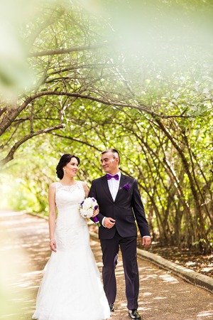 Bride and Groom at wedding Day walking Outdoors on autumn nature. Bridal couple, Happy Newlywed woman and man embracing in green park. Loving wedding couple outdoor.の写真素材
