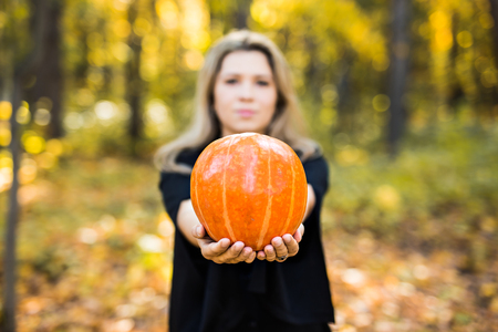 portrait of dramatic beautiful blond young woman holding pumpkin in forest. Halloween dayの写真素材