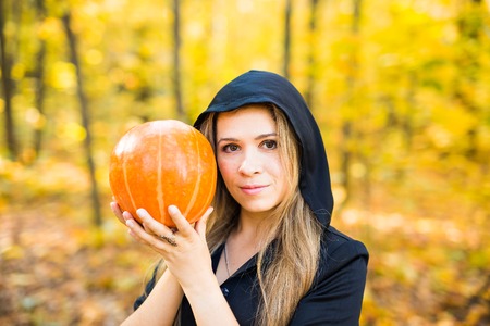 portrait of dramatic beautiful blond young woman holding pumpkin in forest. Halloween dayの写真素材