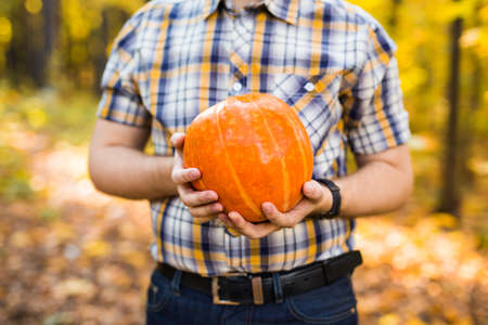 Smiling man carrying pumpkin in a parkの写真素材