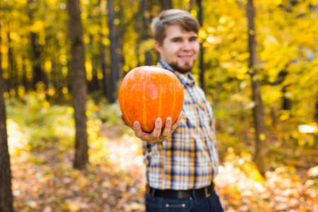 Smiling man carrying pumpkin in a parkの写真素材