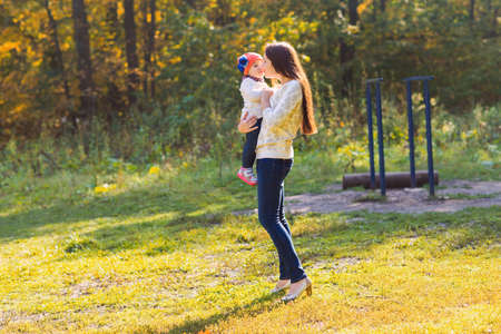 Young beautiful mother walking with her baby in an autumn park