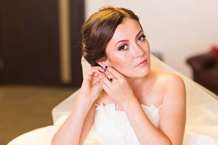 Beautiful young bride with wedding makeup and hairstyle, newlywed woman final preparation for...