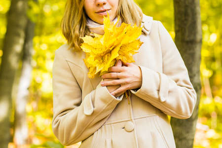 Young woman with autumn leaves in handの写真素材