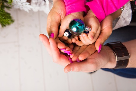 Adult and child hands holding christmas bauble - holidays in  the family conceptの写真素材