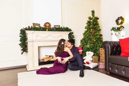 pregnant woman with her husband near the Christmas treeの写真素材