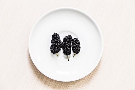 fresh black mulberrie in a white plateの写真素材