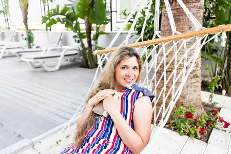 Happy girl resting in hammock near the pool
