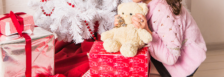 Girl Hugging Teddy Bear near christmas tree.の写真素材