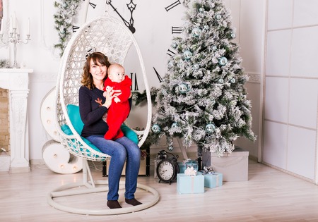 Portrait of smiling young mother with beautiful baby  near Christmas treeの写真素材