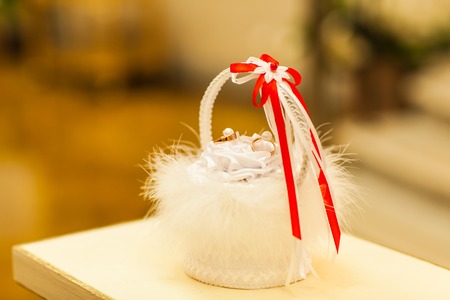 Two wedding rings in a basket with a featherの写真素材