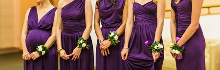 five bridesmaids in purple dresses with  bracelets of flowersの写真素材