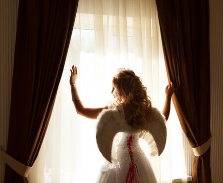 Portrait of beautiful blonde woman with angel's wings. Angel with long curly hair.の写真素材