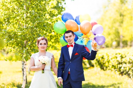 Happy bride and groom with  balloons in the parkの写真素材