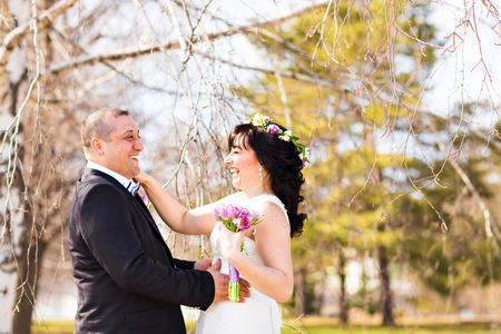 Portrait of happy laughing bride and groom on street at sunny day.の写真素材