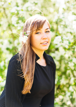 Beautiful young woman over white blossom tree, outdoors spring portrait.