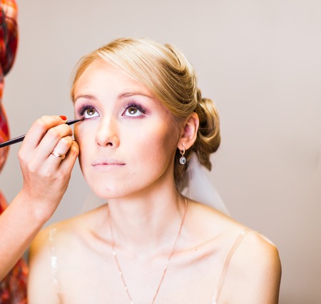 Make-up artist doing make up for young beautiful bride applying wedding make-up.の写真素材
