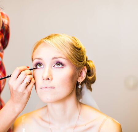 makeup artist preparing bride before the wedding in a morning.の写真素材