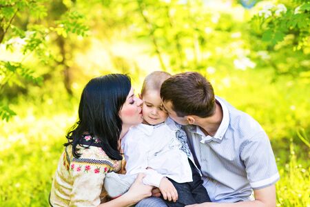 happy mother and father kissing his little son  in park.の写真素材