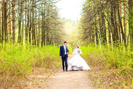 Bride and Groom at wedding Day walking Outdoors on spring nature. Bridal couple, Happy Newlywed woman and man embracing in green park. Loving wedding couple outdoorの写真素材