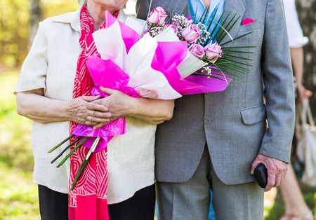 elderly couple with flowers, woman holding bouquet.の写真素材