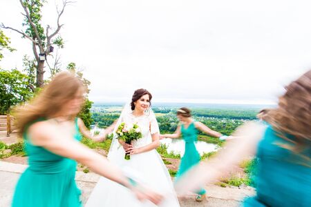 portrait of bride  dancing and having fun with bridesmaids  in green sunny park.の写真素材