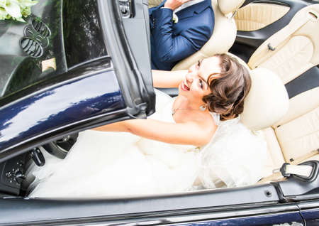 Beautiful young couple bride and groom posing in cabriolet.の写真素材