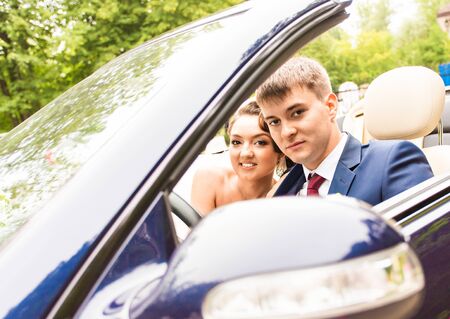 Beautiful young couple bride and groom posing in cabriolet.の写真素材