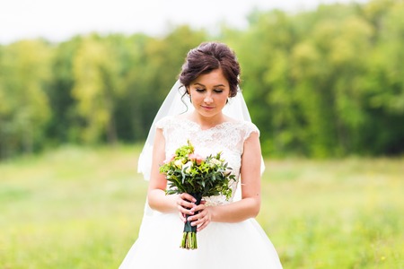 Smiling young bride holding big wedding bouquetの写真素材