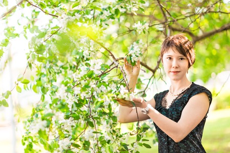 Romantic young woman in the spring garden among apple blossom.