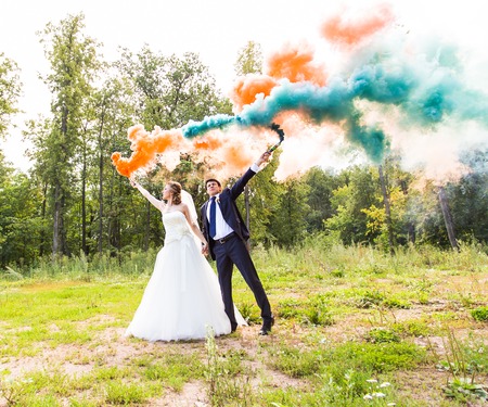 Wedding couple with color smoke in the summer parkの写真素材