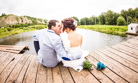 Beautiful young wedding couple sitting on the pier.の写真素材
