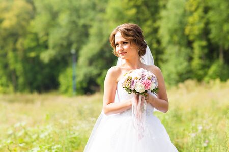Beautiful bride with bouquet of flowers outdoor.の写真素材
