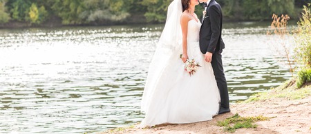 Wedding couple standing and hugging near lakeの写真素材