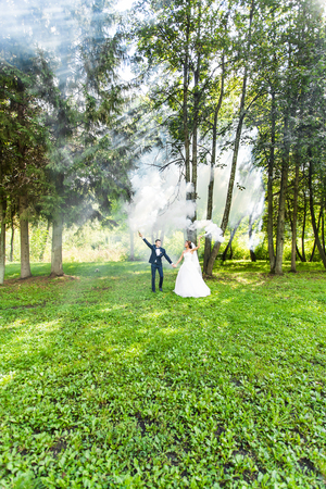 Wedding, love, relationships, marriage. Smiling bride and groom dancing in blue smokeの写真素材