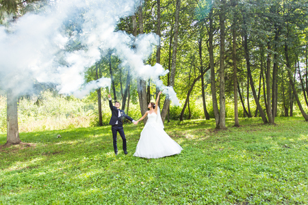 Wedding, love, relationships, marriage. Smiling bride and groom dancing in blue smokeの写真素材