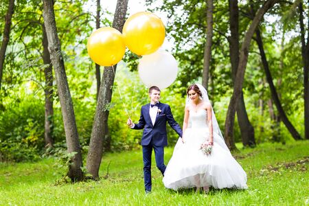 groom  and bride  with balloons  on  green fieldの写真素材